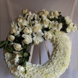 White floral funeral wreath on a stand with roses and lilies