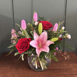 Pink lilies and red roses arranged in a clear glass vase