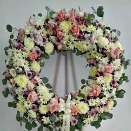 Large floral wreath of white mums and pink roses on a wooden easel with ivory ribbon.