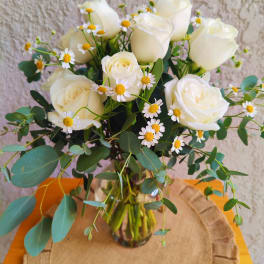 White roses and small daisy flowers in a glass vase