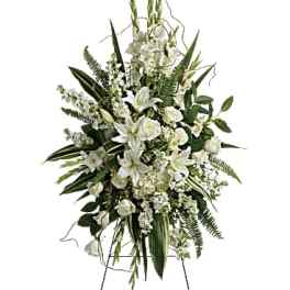 White floral standing spray on an easel with lilies and roses