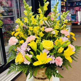 Basket arrangement of yellow lilies, roses, snapdragons, and pink carnations