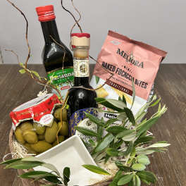 Gift basket with olive oil, olives, crackers, and a small dish