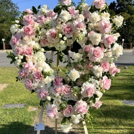 Large heart-shaped floral wreath of pink and white roses on an easel