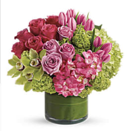 Pink roses and tulips arranged in a green glass vase
