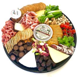 Charcuterie tray with crackers, cheeses, meats, olives, nuts, and vegetables