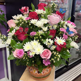 Pink and red rose bouquet with white daisies in a painted vase