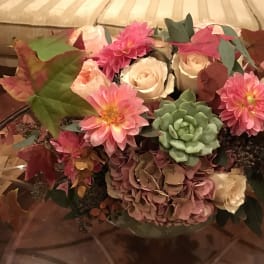 Bouquet of pink and cream flowers with a green succulent in a vase