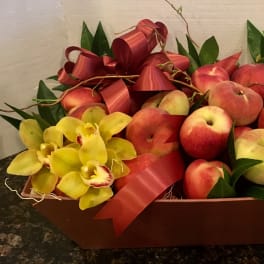 Fruit gift basket with peaches and yellow orchids in a brown tray