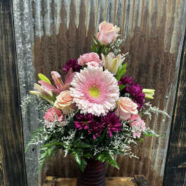 Pink and purple mixed flower arrangement in a tall vase