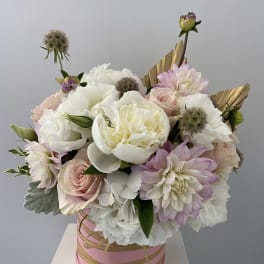 Pink and white bouquet in a round pink box with gold ribbon