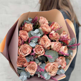 Bouquet of peach roses with eucalyptus in pastel wrapping