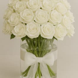 White rose bouquet in a clear glass vase with a white ribbon