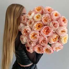 Large bouquet of blush and peach roses held by a woman