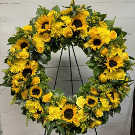 Large yellow floral wreath on a stand with sunflowers and roses