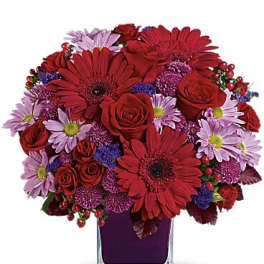 Red and lavender mixed bouquet in a clear square vase