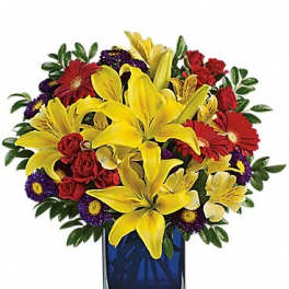 Bouquet of yellow lilies, red roses, and purple daisies in a blue glass vase