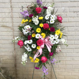 Standing floral spray with roses, daisies, and a pink ribbon