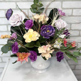Bouquet of purple, pink, and cream flowers in a white vase