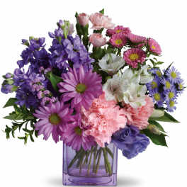 Mixed bouquet of purple, pink, and white flowers in a purple glass vase