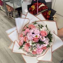 Pink roses and daisies wrapped in white paper with blush trim