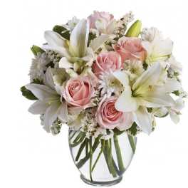 Pink roses and white lilies arranged in a clear glass vase