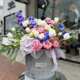 Mixed bouquet in a gray hatbox with pink, white, purple, and blue flowers