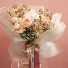 Peach and white rose bouquet wrapped in translucent paper