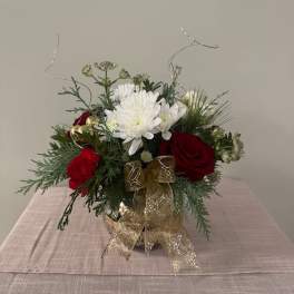 Red roses and white chrysanthemums in a gold vase with a ribbon