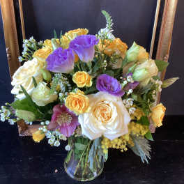 Bouquet of roses and purple lisianthus in a clear glass vase