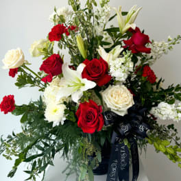 Red and white roses with lilies in a black vase