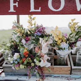 Assorted wildflower bouquets in glass vases on a wooden display