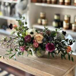 Low floral arrangement with roses and anemone in a white vase