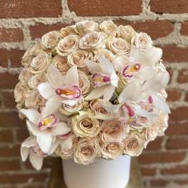 Cream roses and white orchids arranged in a white hat box
