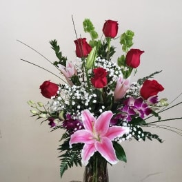 Mixed bouquet of red roses and pink lilies in a glass vase