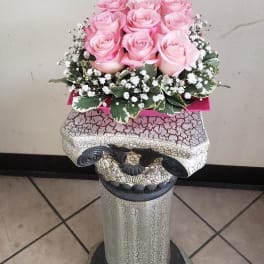 Pink roses arranged in a decorative pedestal container