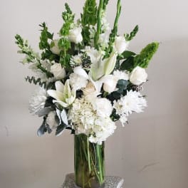White floral arrangement in a clear glass vase on a pedestal