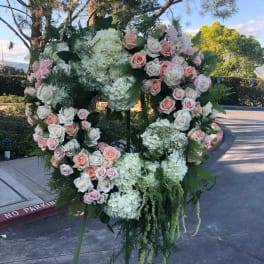 Large floral wreath on an easel with pink and white roses and hydrangeas