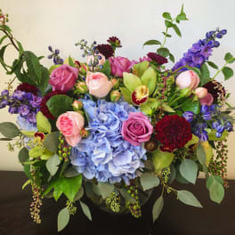 Mixed bouquet with pink roses, blue hydrangea, and purple flowers in a vase