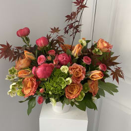 Bouquet of pink and orange roses with green hydrangea in a white vase