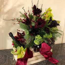 Holiday floral arrangement in a wooden crate with orchids and velvet ribbon
