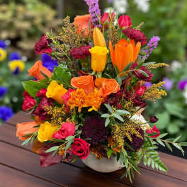 Colorful bouquet of roses, lilies, and mums in a white vase