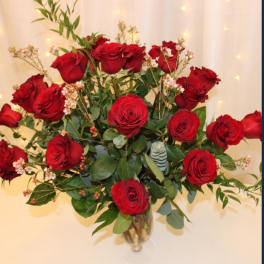 Red roses arranged in a clear glass vase with greenery