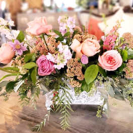 Pink and lavender roses arranged in a white decorative container