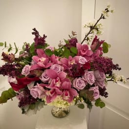 Pink orchids and lavender roses in a glass vase