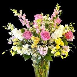 Mixed bouquet of pink, white, and yellow flowers in a clear glass vase