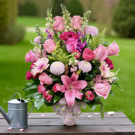 Pink mixed flower arrangement in a glass vase with a ribbon
