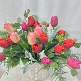 Bouquet of multicolored tulips in a white basket vase