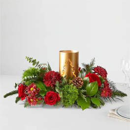 Red flowers and greenery arranged around a gold candle holder