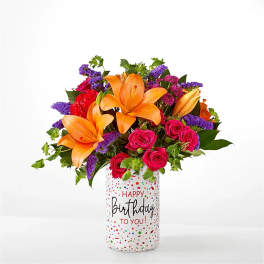 Bouquet of orange lilies and pink roses in a birthday vase